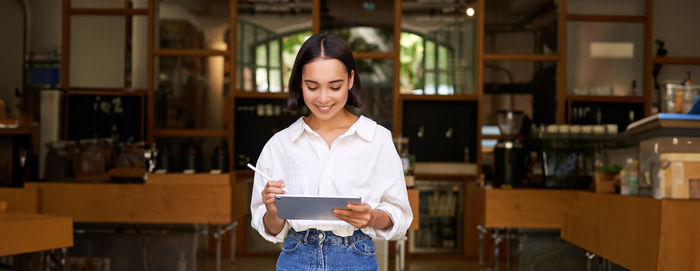 Portrait of young woman standing in library