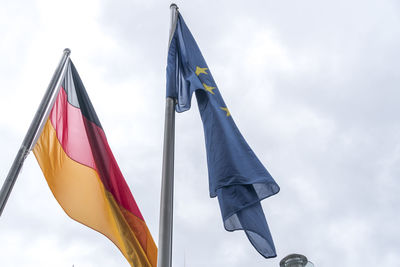 Low angle view of flags against cloudy sky