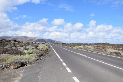 Road leading towards mountain against sky