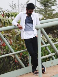 Man standing by railing against plants