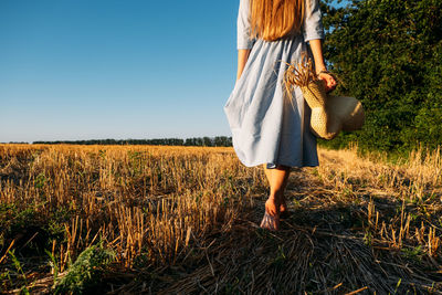 Rear view of woman standing on field against clear sky