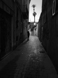 Woman walking on footpath amidst buildings in city