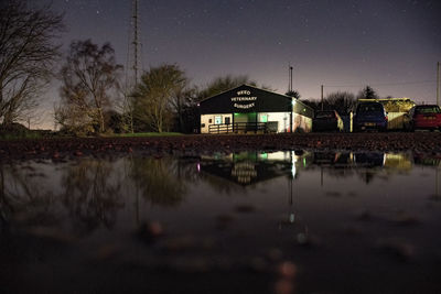 House by lake against sky at night
