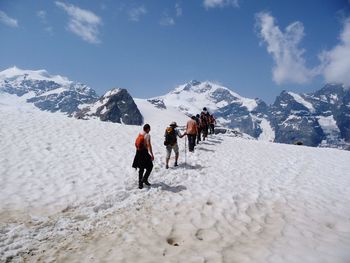 People walking on snowcapped mountain against sky