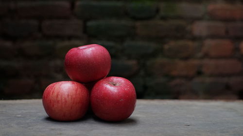 Close-up of apples on table against wall