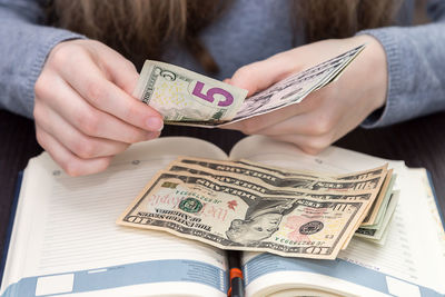 Midsection of woman holding paper with text on table