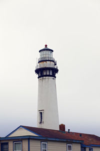 Low angle view of lighthouse by building against sky