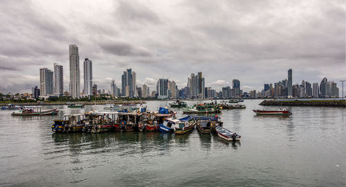 Boats moored in river with city in background