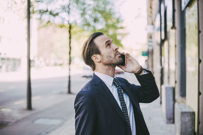 Side view of businessman talking on phone in city