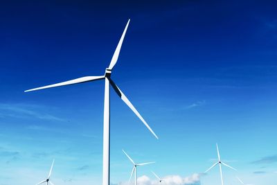 Low angle view of wind turbines against sky