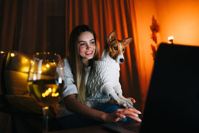 Happy woman with dog working on laptop at home