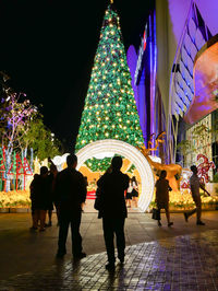 People standing by illuminated building at night