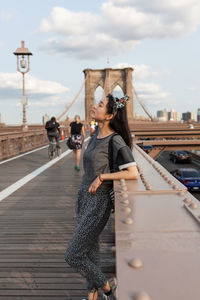 Side view of woman leaning on railing at brooklyn bridge