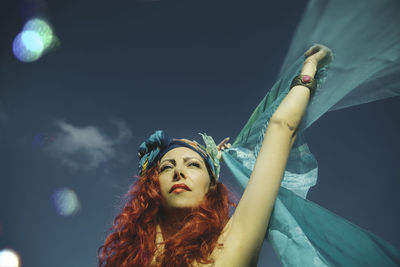 Portrait of a young woman looking away against sky