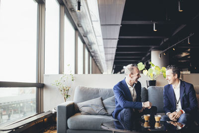 Happy entrepreneur talking to colleague while sitting in office