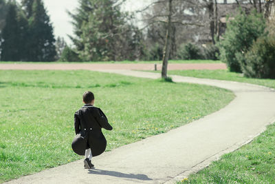 Rear view of boy walking on footpath at park