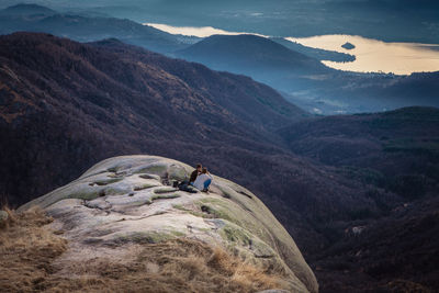 High angle view of couple sitting on rock by mountains