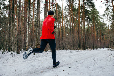 Rear view of man walking on snow covered landscape