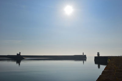 Silhouette harbour wall over sea against sky