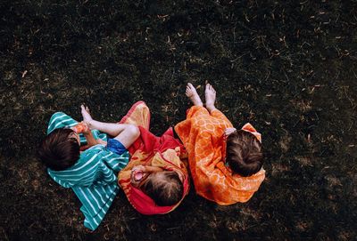 Directly above shot of siblings sitting on grass