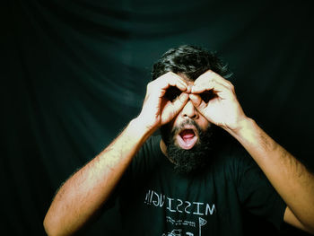 Portrait of man making face against black background