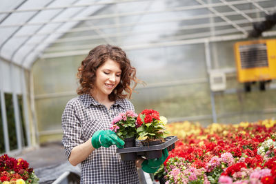 Close-up of smiling young woman standing in greenhouse