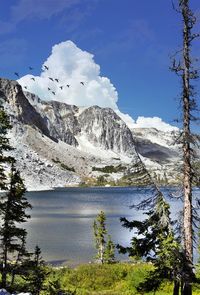 Scenic view of lake by snowcapped mountains against sky