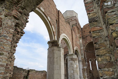 Low angle view of old ruin building against cloudy sky