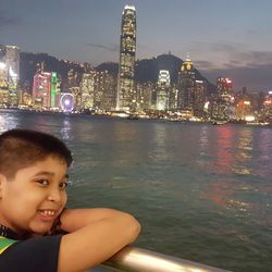 Portrait of boy with illuminated cityscape in water