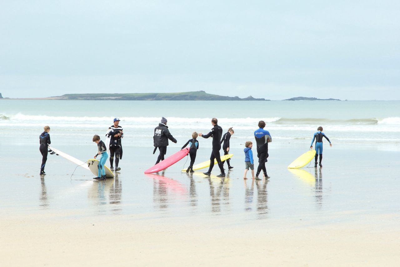 water, sea, beach, horizon over water, lifestyles, leisure activity, men, shore, reflection, clear sky, vacations, enjoyment, togetherness, person, copy space, waterfront, large group of people, wave, boys