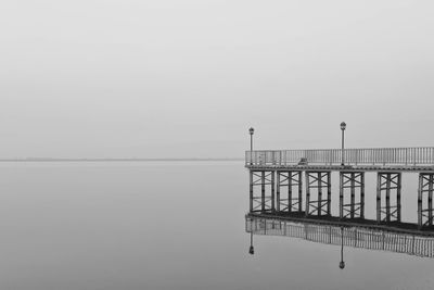 Pier by calm lake against sky