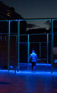 Rear view of man with umbrella walking at night