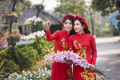 Portrait of smiling young woman standing by flowering plants