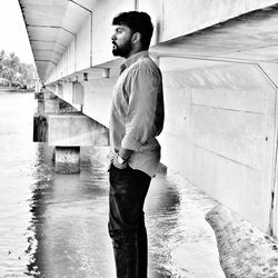 Man standing by bridge over river