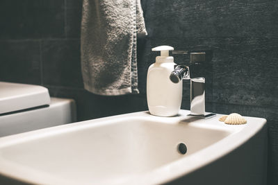 Closeup view of a bidet with rolled up towel, soap dispenser. modern environment bathroom fixtures 