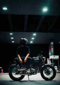 Side view of man riding motor scooter on street at night