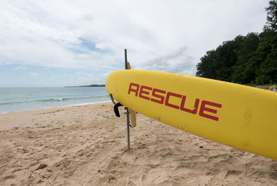 Information sign on beach against sky