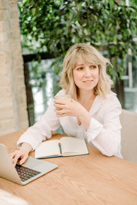 Portrait of smiling woman using mobile phone on table