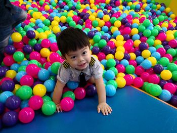 Cute smiling boy looking away while playing with colorful balls