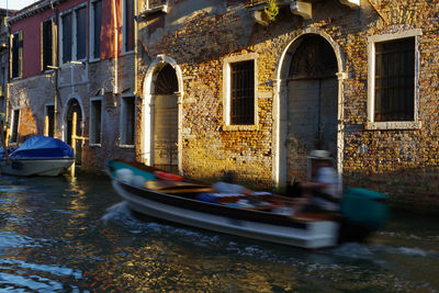 Boats moored in canal amidst buildings in city