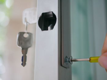 Cropped hands of person adjusting lock on glass door