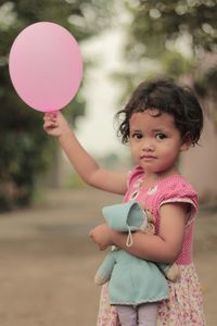 Portrait of cute girl holding balloon while standing outdoors