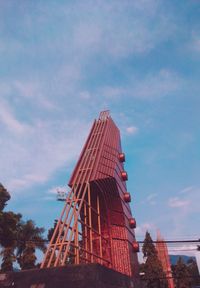 Low angle view of red building against cloudy sky