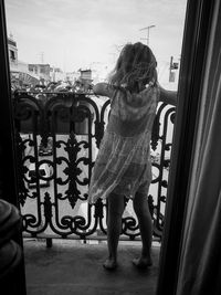 Rear view of woman standing against window