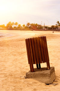 Deck chairs on beach against sky during sunset