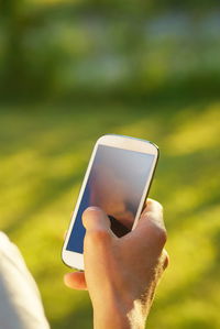 Close-up of hand holding smart phone outdoors