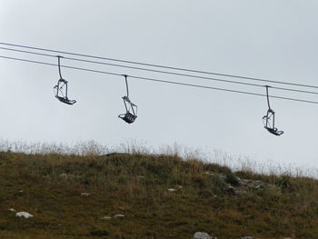 Low angle view of chair lift against foggy sky