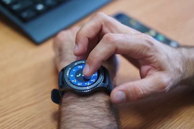 Cropped hand of man touching smart watch