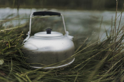 Close-up of tea light on field by water