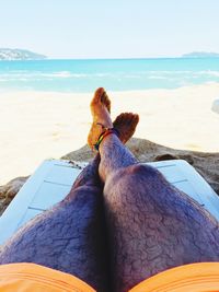 Low section of man on beach against clear sky